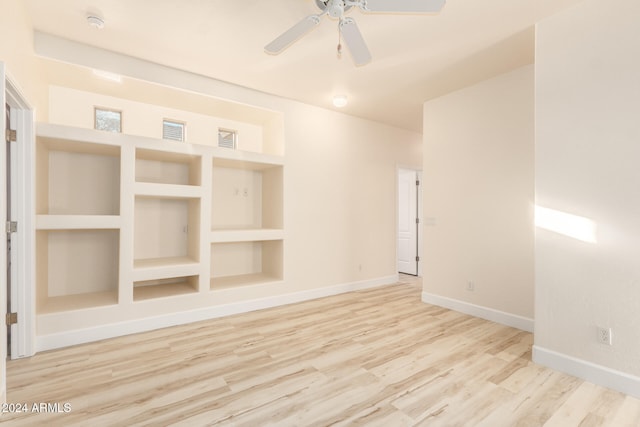 unfurnished room featuring wood-type flooring, built in features, and ceiling fan