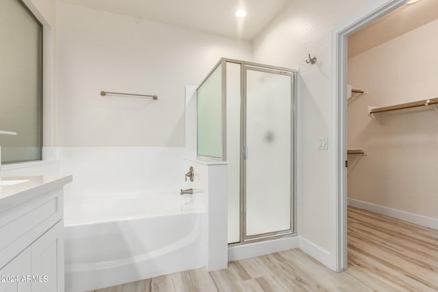 bathroom with plus walk in shower, hardwood / wood-style floors, and vanity