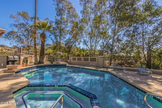 view of pool featuring an in ground hot tub, a grill, and a mountain view