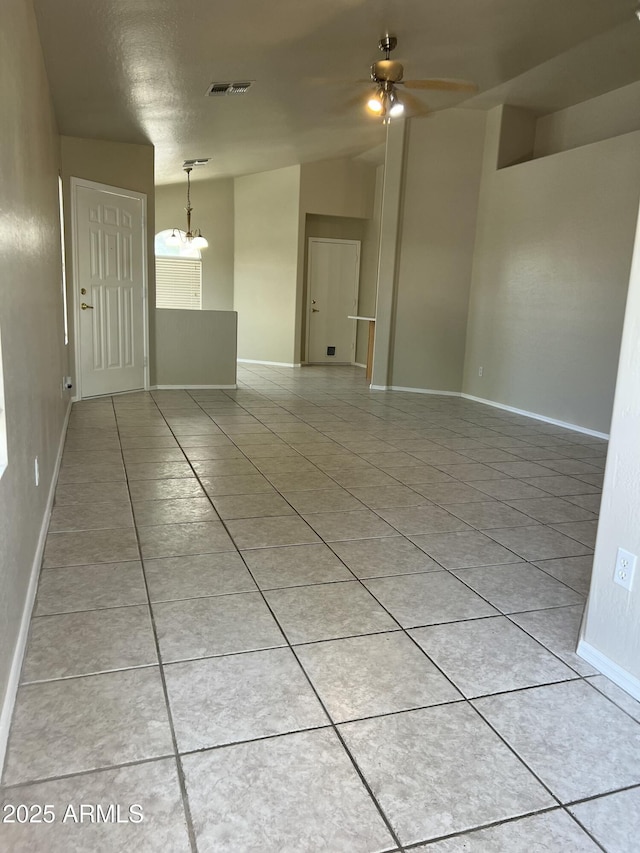 unfurnished room with vaulted ceiling, ceiling fan with notable chandelier, light tile patterned floors, baseboards, and visible vents