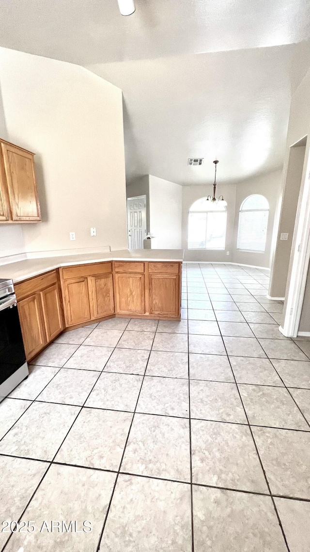 kitchen with a peninsula, light tile patterned flooring, stainless steel range with electric cooktop, vaulted ceiling, and light countertops