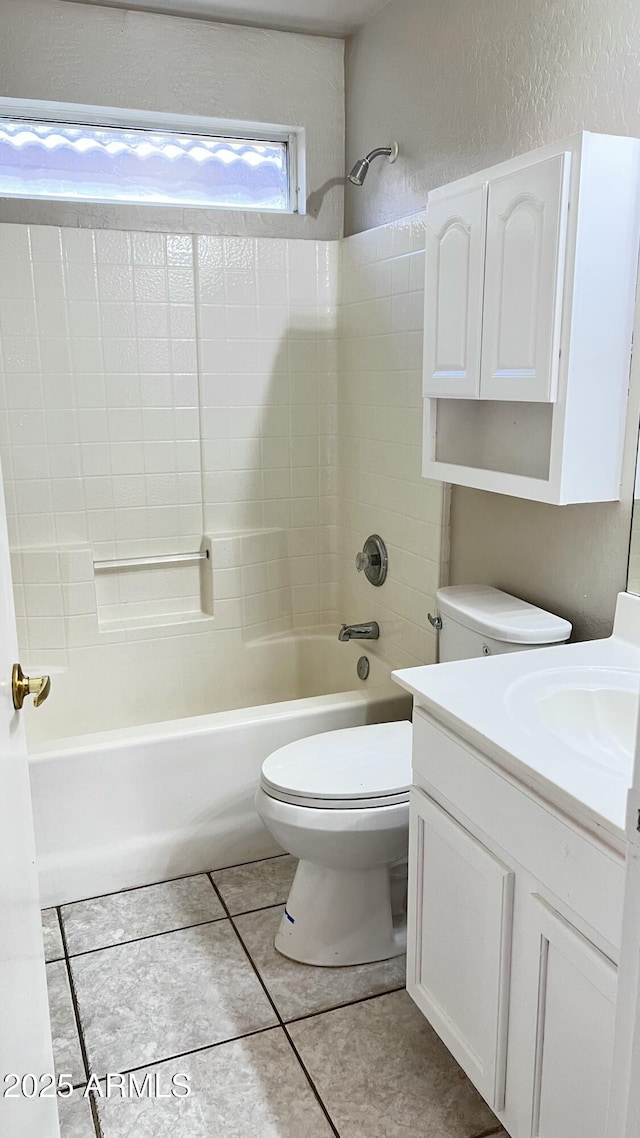 full bath featuring washtub / shower combination, tile patterned flooring, a textured wall, toilet, and vanity