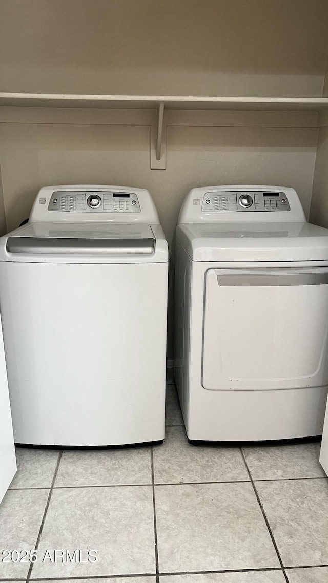 washroom featuring washing machine and dryer, light tile patterned flooring, and laundry area