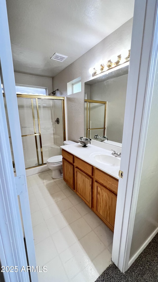 bathroom featuring a shower stall, a sink, visible vents, and double vanity