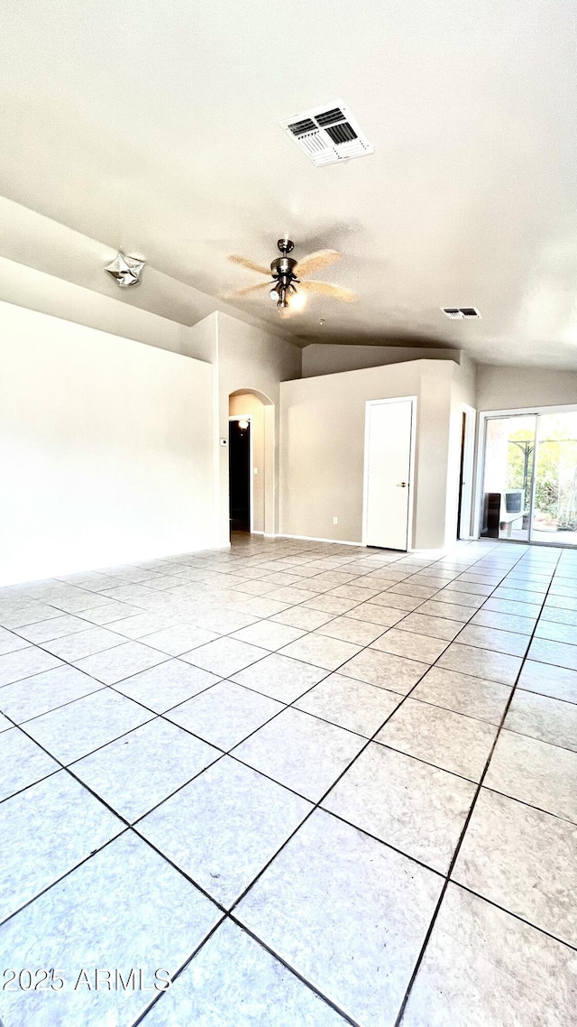 empty room with ceiling fan, visible vents, arched walkways, and light tile patterned floors