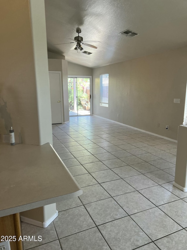 empty room featuring visible vents, a textured ceiling, ceiling fan, and light tile patterned floors
