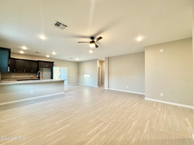 unfurnished living room featuring light hardwood / wood-style floors, sink, and ceiling fan