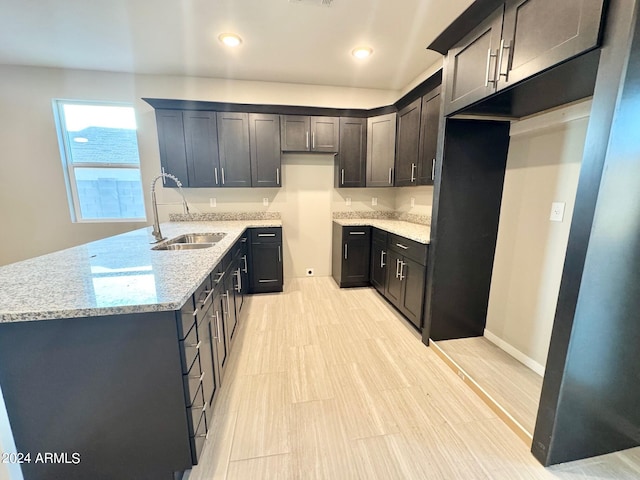 kitchen featuring sink, light stone counters, and light wood-type flooring