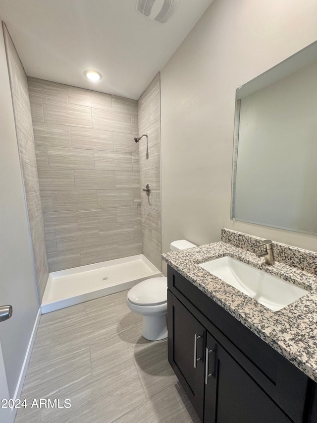 bathroom with toilet, vanity, and tiled shower