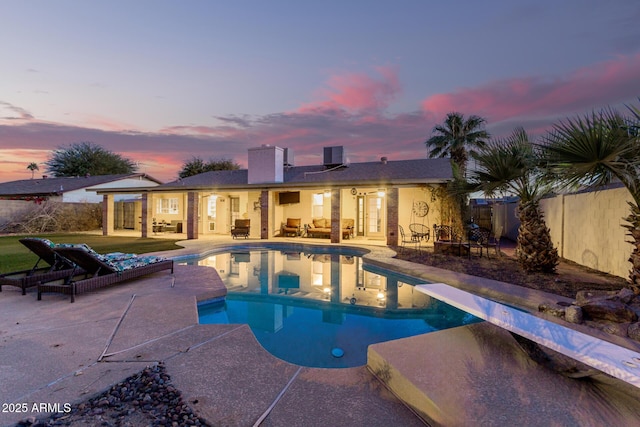 pool at dusk with a diving board and a patio