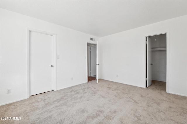 unfurnished bedroom featuring light carpet and a spacious closet