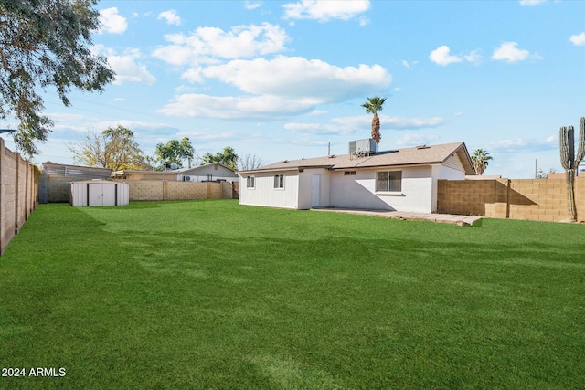 rear view of property featuring a lawn and a storage unit