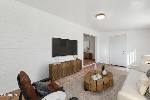 living room featuring light tile patterned flooring and brick wall