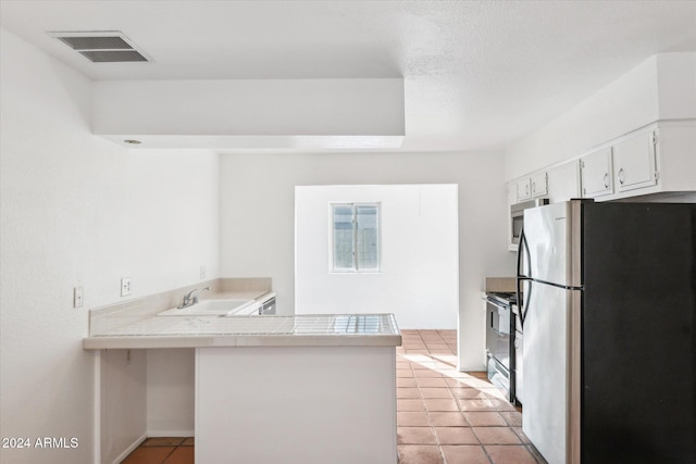 kitchen featuring white cabinetry, sink, kitchen peninsula, light tile patterned floors, and appliances with stainless steel finishes