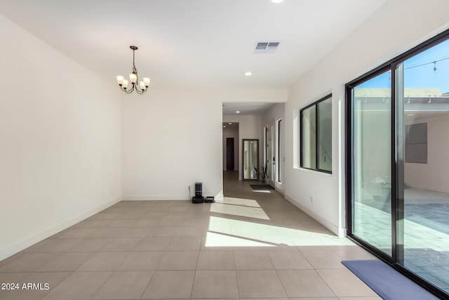 spare room with a notable chandelier and light tile patterned floors