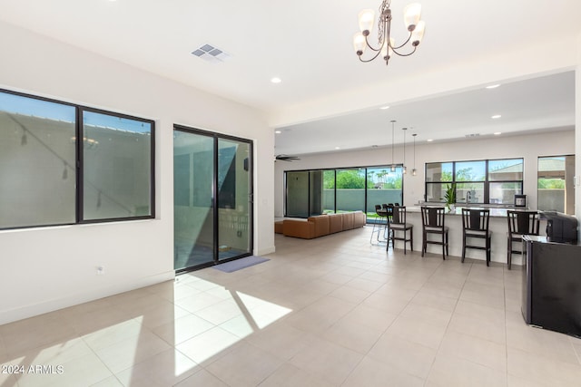 living room with a healthy amount of sunlight, light tile patterned flooring, and ceiling fan with notable chandelier