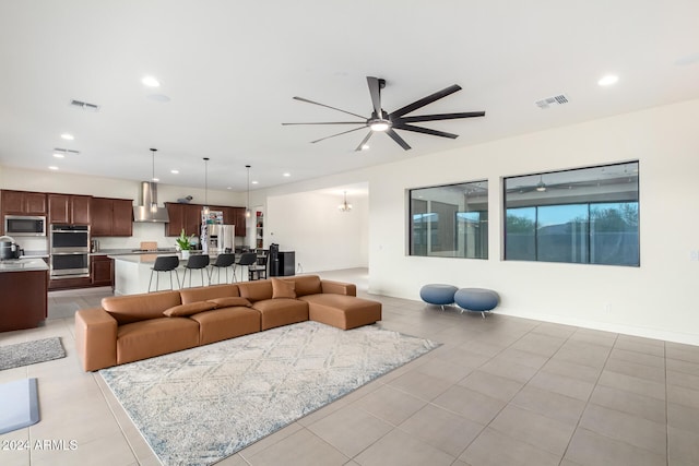 tiled living room with a wealth of natural light and ceiling fan with notable chandelier