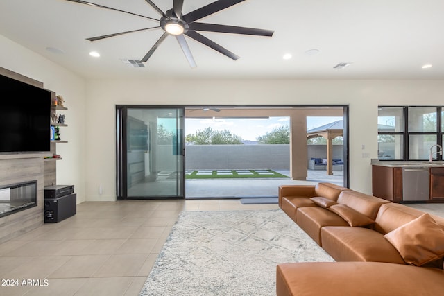 living room with sink, light tile patterned flooring, a fireplace, and ceiling fan