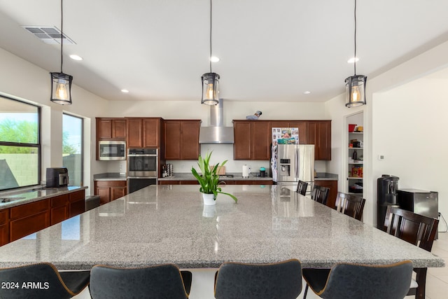 kitchen with stainless steel appliances, a large island, a breakfast bar, pendant lighting, and light stone counters