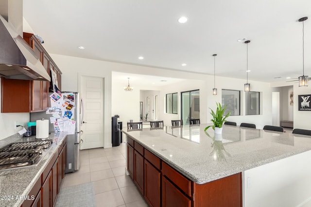 kitchen with a large island, a breakfast bar, wall chimney exhaust hood, and pendant lighting