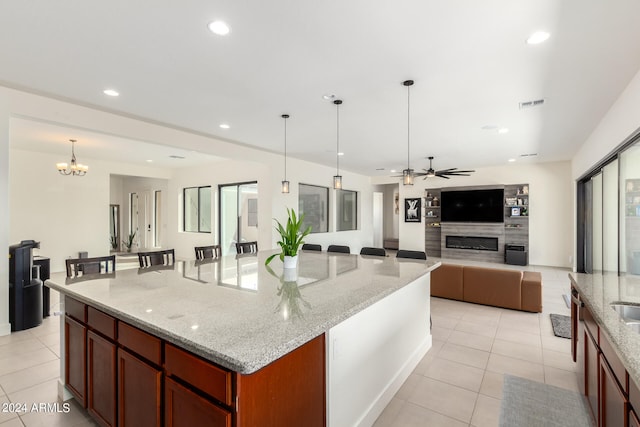 kitchen featuring a center island, pendant lighting, plenty of natural light, light stone counters, and ceiling fan with notable chandelier