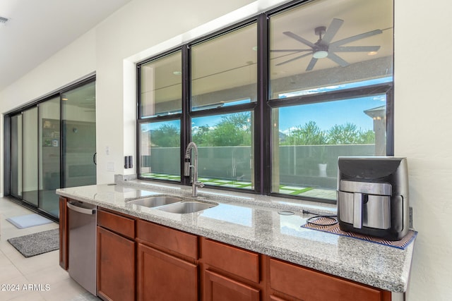 kitchen featuring light stone counters, a healthy amount of sunlight, sink, and light tile patterned floors