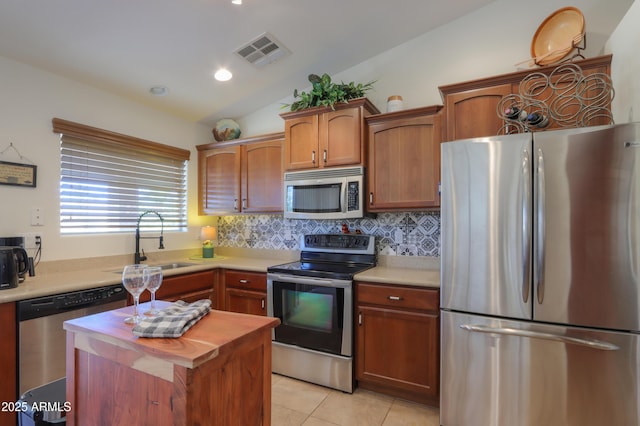 kitchen featuring light tile patterned floors, visible vents, lofted ceiling, a sink, and appliances with stainless steel finishes