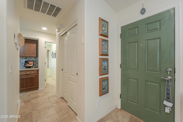 foyer featuring light tile patterned floors, baseboards, and visible vents