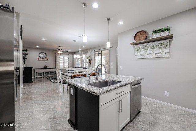 kitchen featuring appliances with stainless steel finishes, white cabinetry, sink, a kitchen island with sink, and light stone countertops