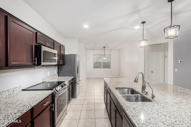 kitchen with hanging light fixtures, light tile patterned floors, appliances with stainless steel finishes, and a sink