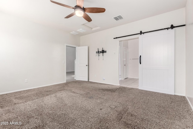 empty room featuring visible vents, light carpet, a ceiling fan, a barn door, and attic access