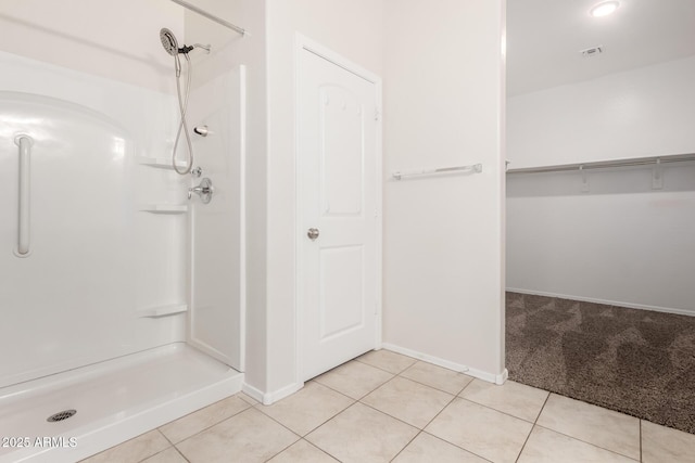 bathroom featuring tile patterned floors, visible vents, baseboards, and walk in shower