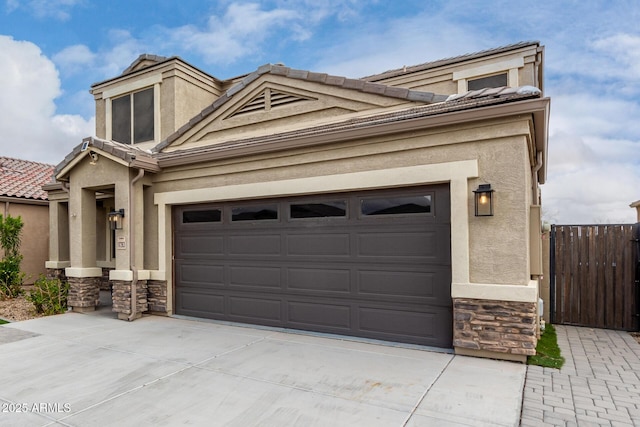 view of front of house featuring stone siding, stucco siding, concrete driveway, and a tile roof