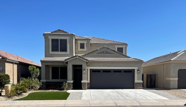 view of front of house featuring stone siding, stucco siding, a tiled roof, and an attached garage