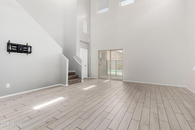 unfurnished living room featuring visible vents, baseboards, stairs, and light wood finished floors