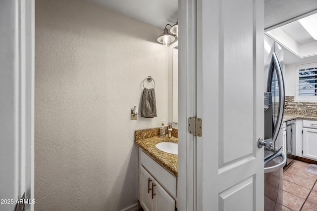 bathroom with tile patterned flooring, vanity, and a textured wall