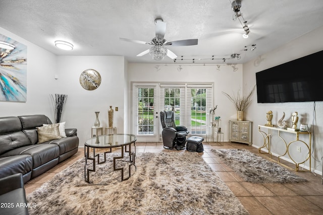 living area with a textured ceiling, ceiling fan, and tile patterned flooring