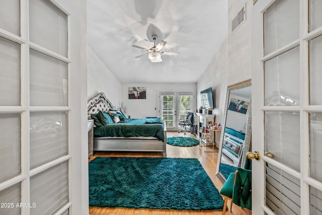 bedroom with access to exterior, wood finished floors, visible vents, and ceiling fan