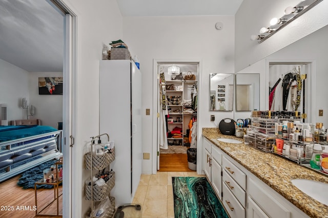 full bathroom with double vanity, a spacious closet, and a sink