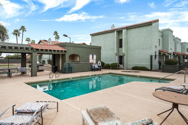 pool with a patio area and fence