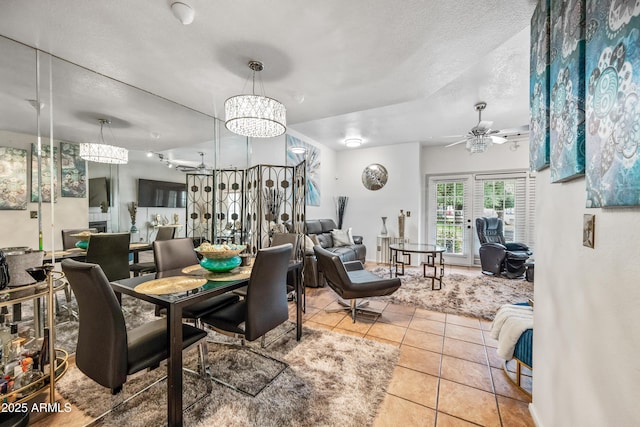 dining area with tile patterned flooring, ceiling fan with notable chandelier, and a textured ceiling