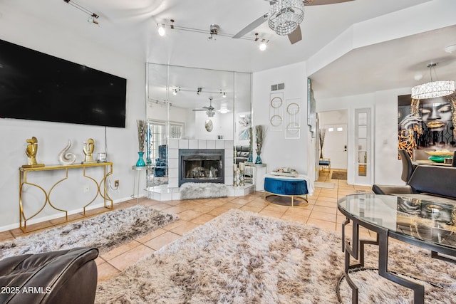 living room with tile patterned floors, visible vents, a ceiling fan, a fireplace, and rail lighting