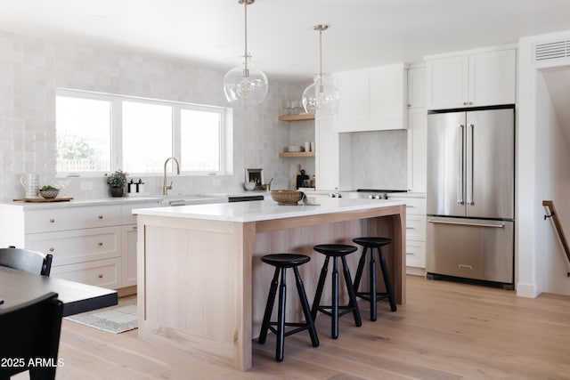 kitchen featuring white cabinetry, a kitchen breakfast bar, a center island, light hardwood / wood-style floors, and high quality fridge