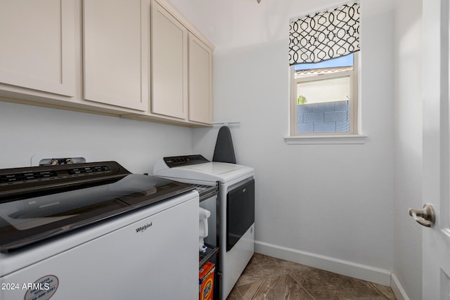 laundry room featuring washing machine and clothes dryer, cabinets, and dark tile patterned flooring