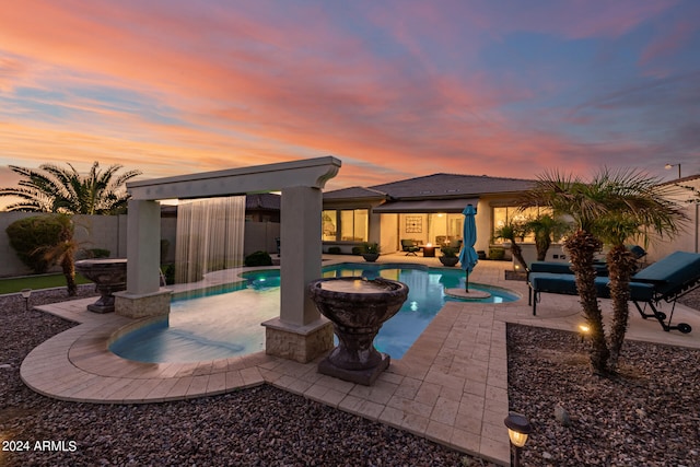 pool at dusk featuring a patio and an outdoor hangout area