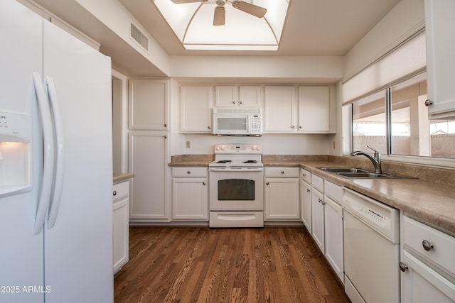 kitchen with dark wood-style flooring, visible vents, white cabinetry, a sink, and white appliances