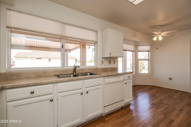 kitchen with dark wood finished floors, light countertops, white cabinets, white dishwasher, and a sink