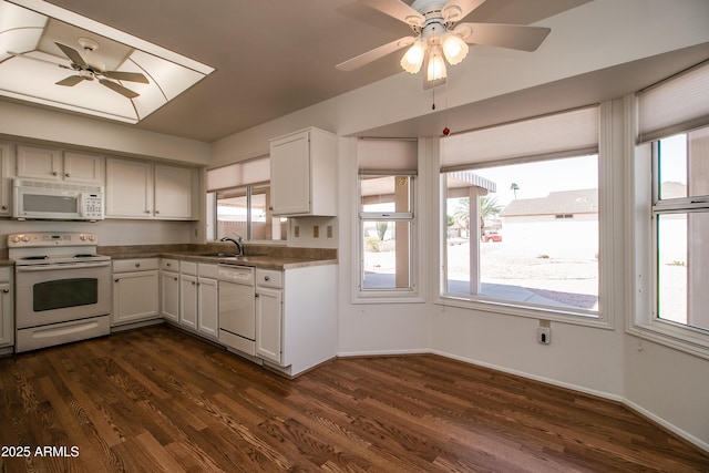 kitchen featuring dark wood-type flooring, a ceiling fan, a sink, white appliances, and baseboards