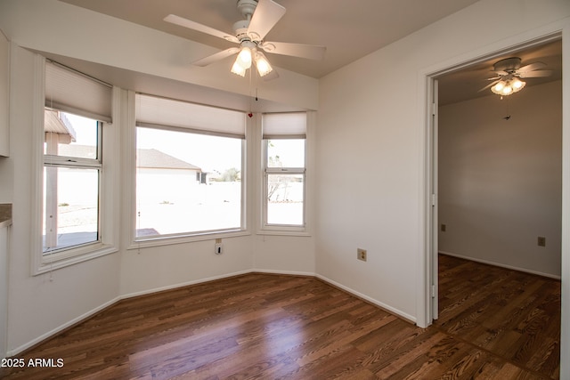 spare room featuring dark wood-style floors, baseboards, and a ceiling fan