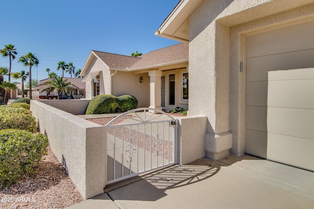 view of property exterior featuring roof with shingles, fence, a gate, and stucco siding